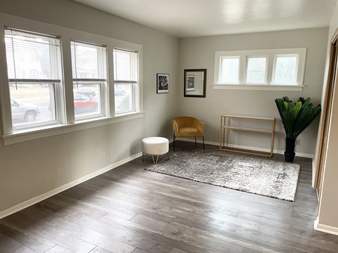 A room with a chair, a plant, and a picture frame on the wall.